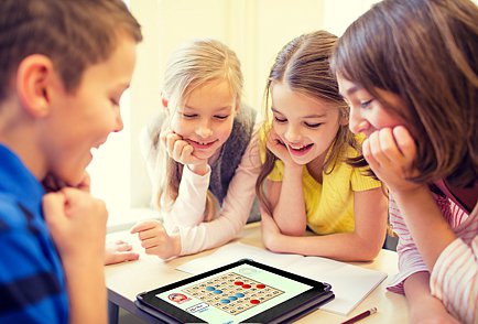 Bilden visar fyra barn som sitter runt ett bord och tittar på en surfplatta